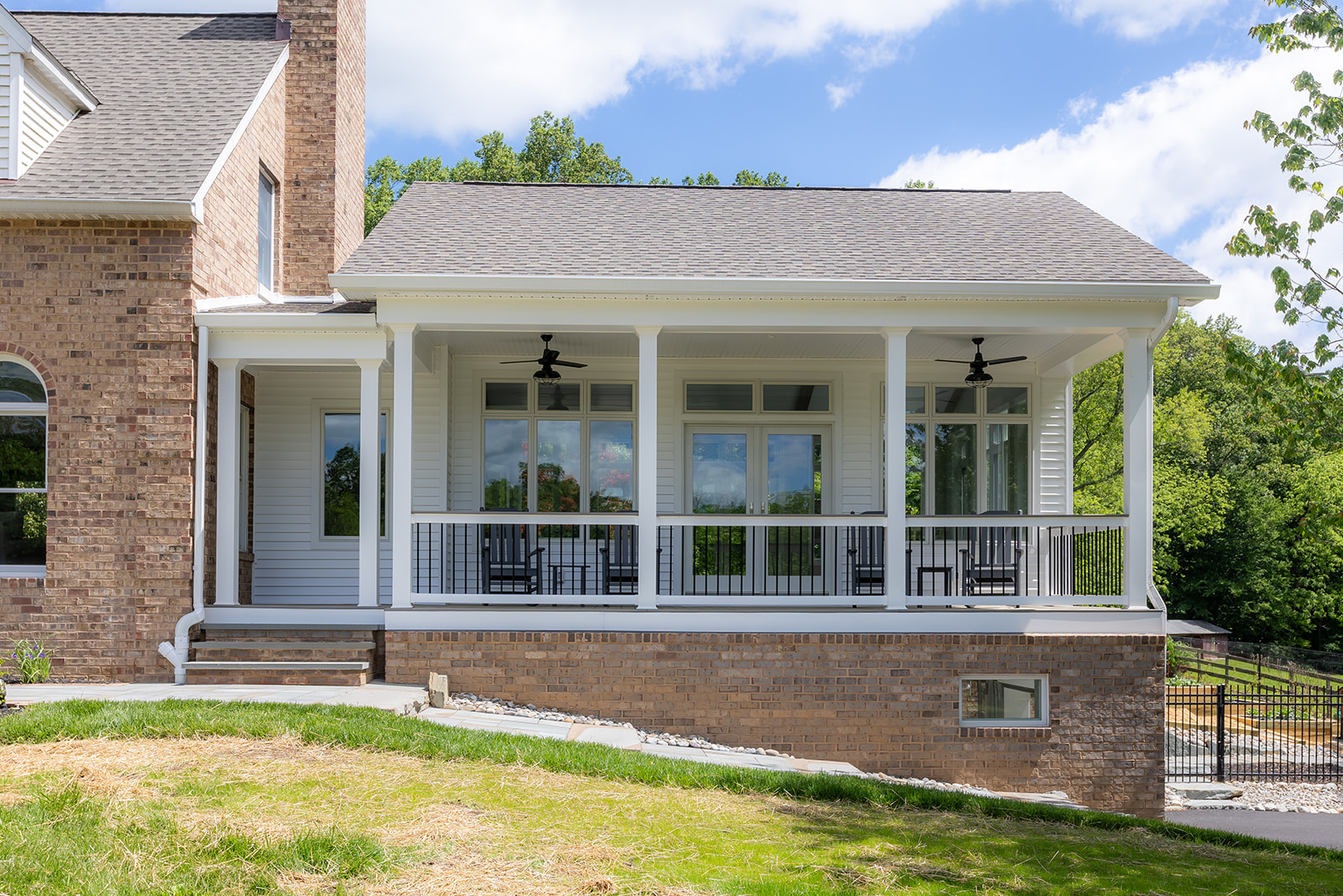 Scherr custom home addition with covered porch, white columns, and brick foundation