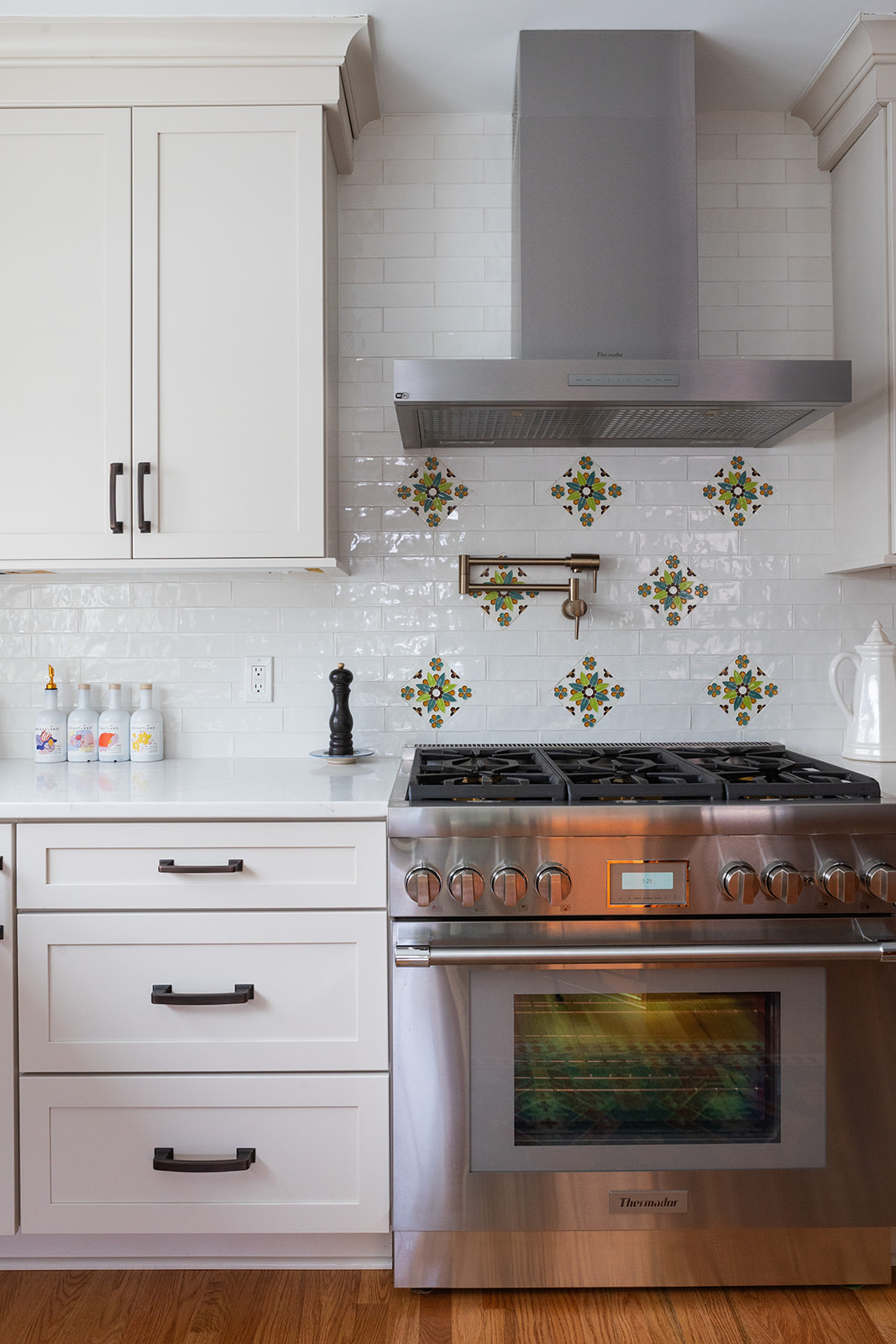 Scherr kitchen remodel with white cabinetry, professional range, and hand-painted tile accents